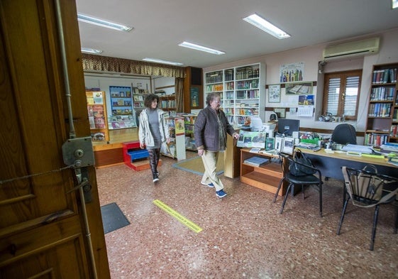 Asun Arabaolaza, con la vicepresidenta de la asociación de vecinos, Virginia Pérez, recogiendo la biblioteca tras su cierre.