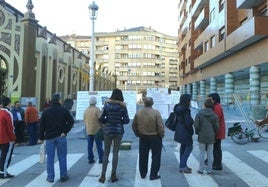 Vecinos de Castro observan los carteles informativos sobre la rehabilitación de la plaza.