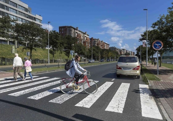 Una mujer cruza en bicicleta por la Avenida de la Constitución (S-20), una de las vías de acceso a Santander.