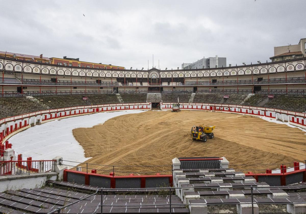 Dos máquinas esparcen la arena llegada desde la localidad palentina de Dueñas.