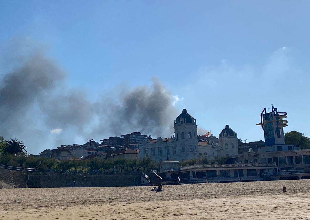 Imagen secundaria 1 - Arriba, momento en el que los bomberos han conseguido controlar el incendio. Abajo, la columna de humo vista desde los Jardines de Pereda y desde El Sardinero.