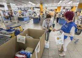 Una mujer entrega a una voluntaria su donación en un supermercado Lupa.