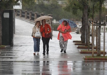 Tres mujeres pasean con sus paraguas por El Sardinero en plena tormenta.