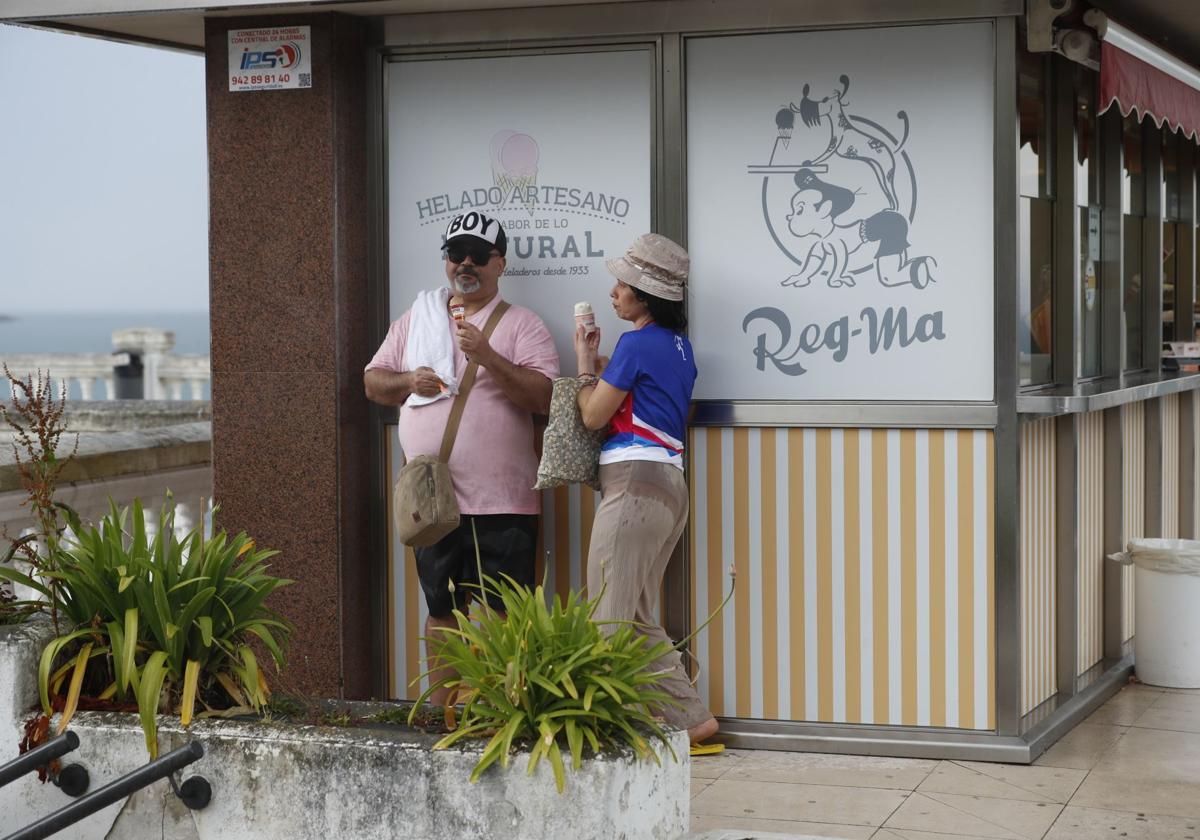 Dos personas se resguardan con sus helados durante la tormenta en El Sardinero.
