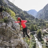 Una mujer cruza un puente tibetano, uno de los pasos más famosos de la vía ferrata de La Hermida, en el municipio de Peñarrubia.