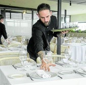 Profesionales de hostelería preparando un comedor para el servicio.