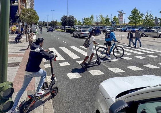 Varios usuarios de patinetes y bicicletas cruzan por un paso de peatones de Marqués de la Hermida.