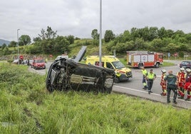 El coche volcado en el lugar del accidente junto a agentes de la Guardia Civil, 061 y Bomberos.