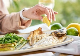 Un cliente exprime un limón a un pescado.
