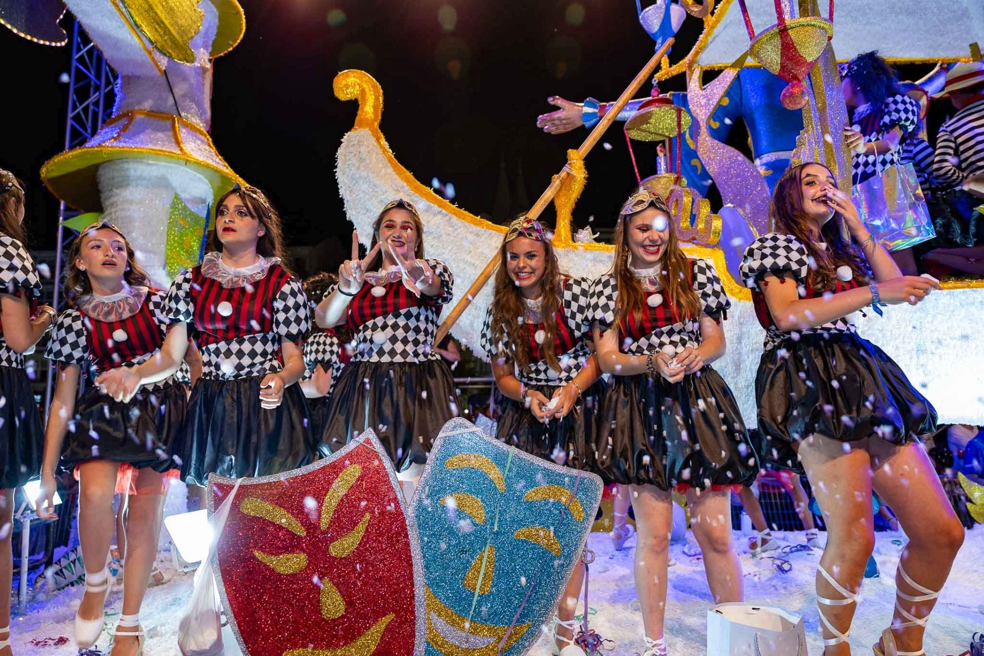 Integrantes de Carnavalescas, con su vestimenta de Arlequín, sobre la alegoría.