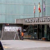 Dos operarios colocan el nuevo letrero de Tribunal de Instancia en el Palacio de Justicia de Torrelavega.