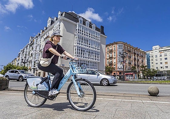 Una joven hace uso de una bicicleta eléctrica municipal por el centro de Santander, en el entorno de Puertochico.