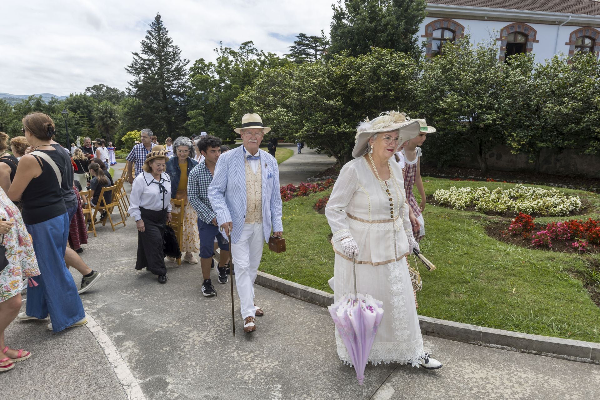 Asistentes a El Retornar del Indiano vestidos para la ocasión, de blanco, con sombrillas de encaje y sombreros de paja.