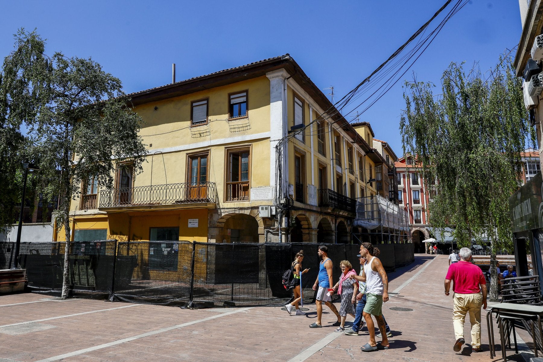 Vecinos caminan junto al edificio municipal de Baldomero Iglesias, definitivamente vallado y en obras, ayer, en Torrelavega.