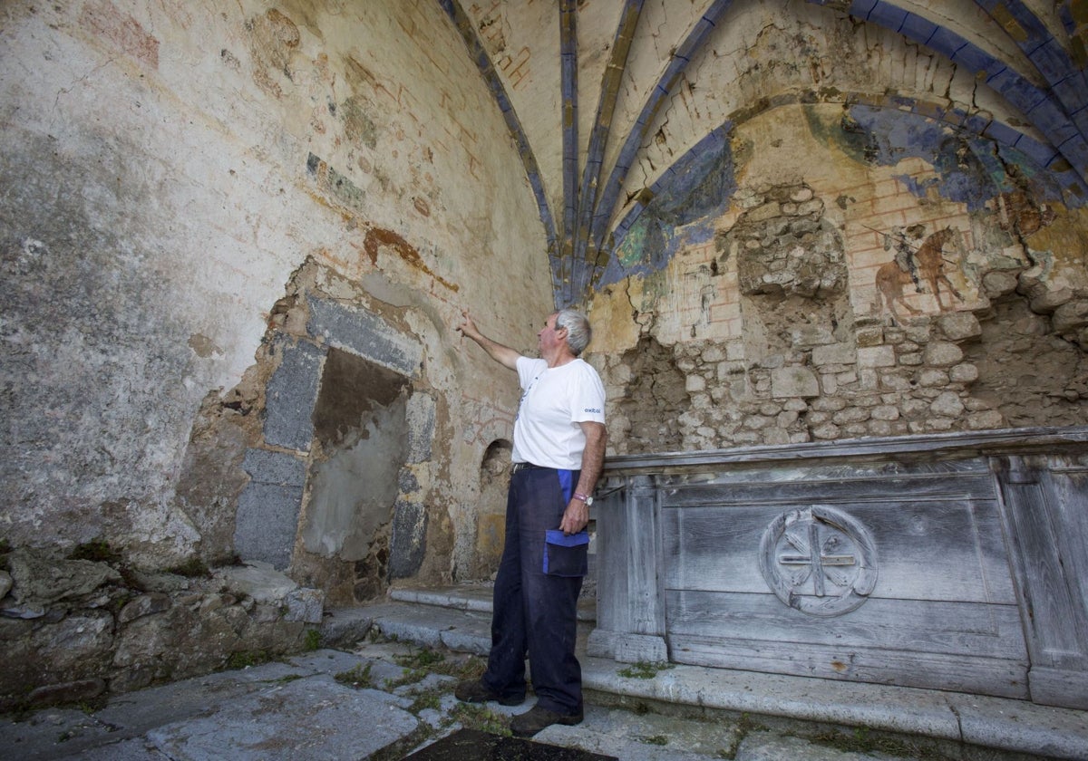 Un hombre señala los murales medievales de la ermita en Ruesga.