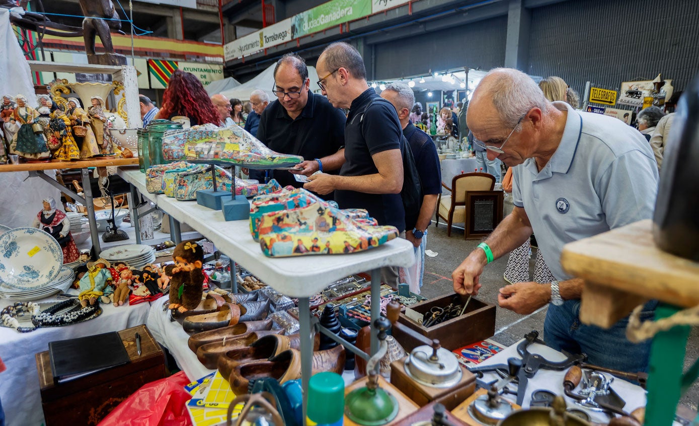 Tres señores se interesan por un puesto de antigüedades.