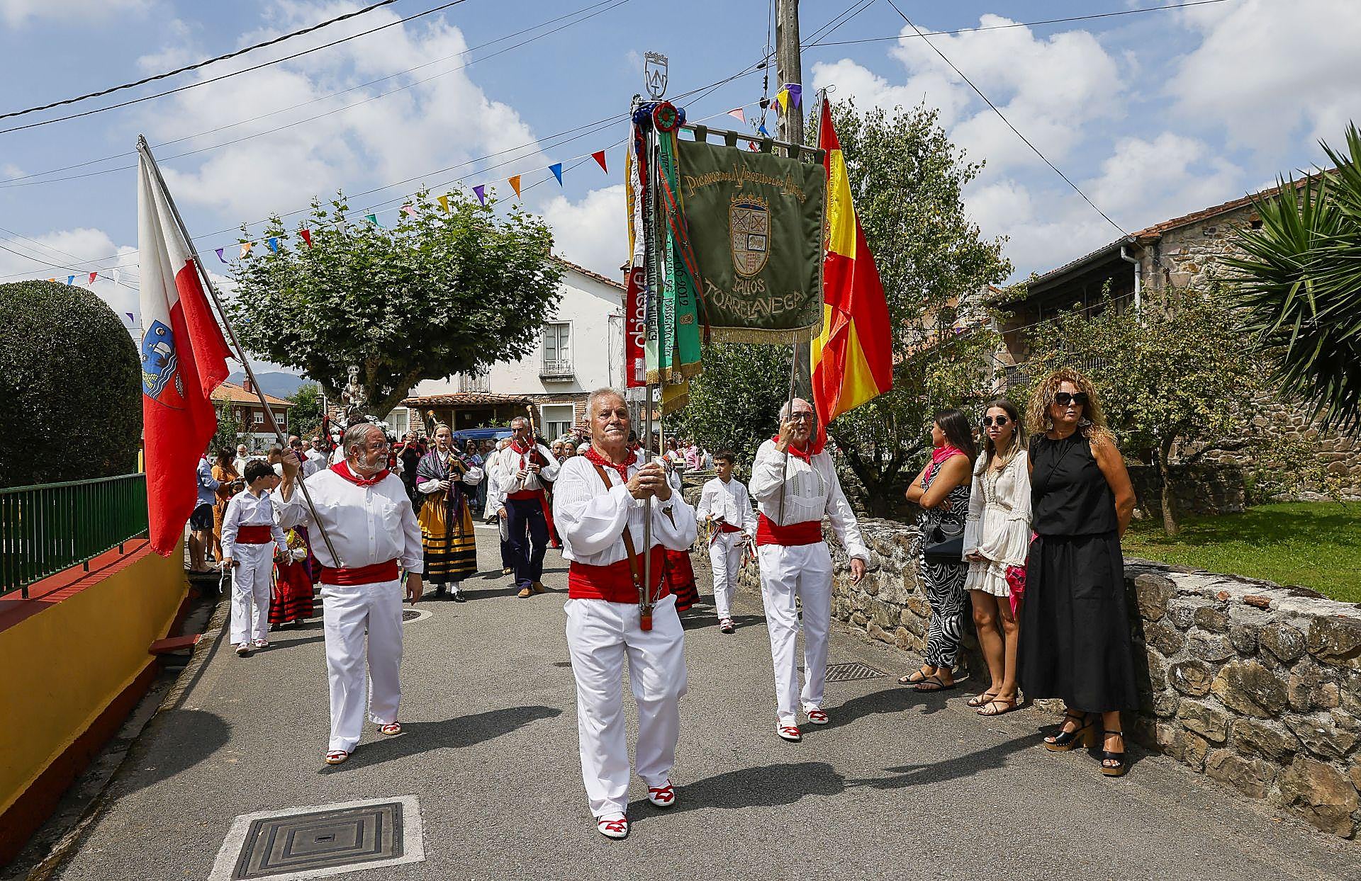 El escudo del municipio y las banderas de Cantabria y de España presidieron en todo momento la procesión.