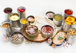 Latas de pescados, legumbres y frutas en conserva listas para consumir.