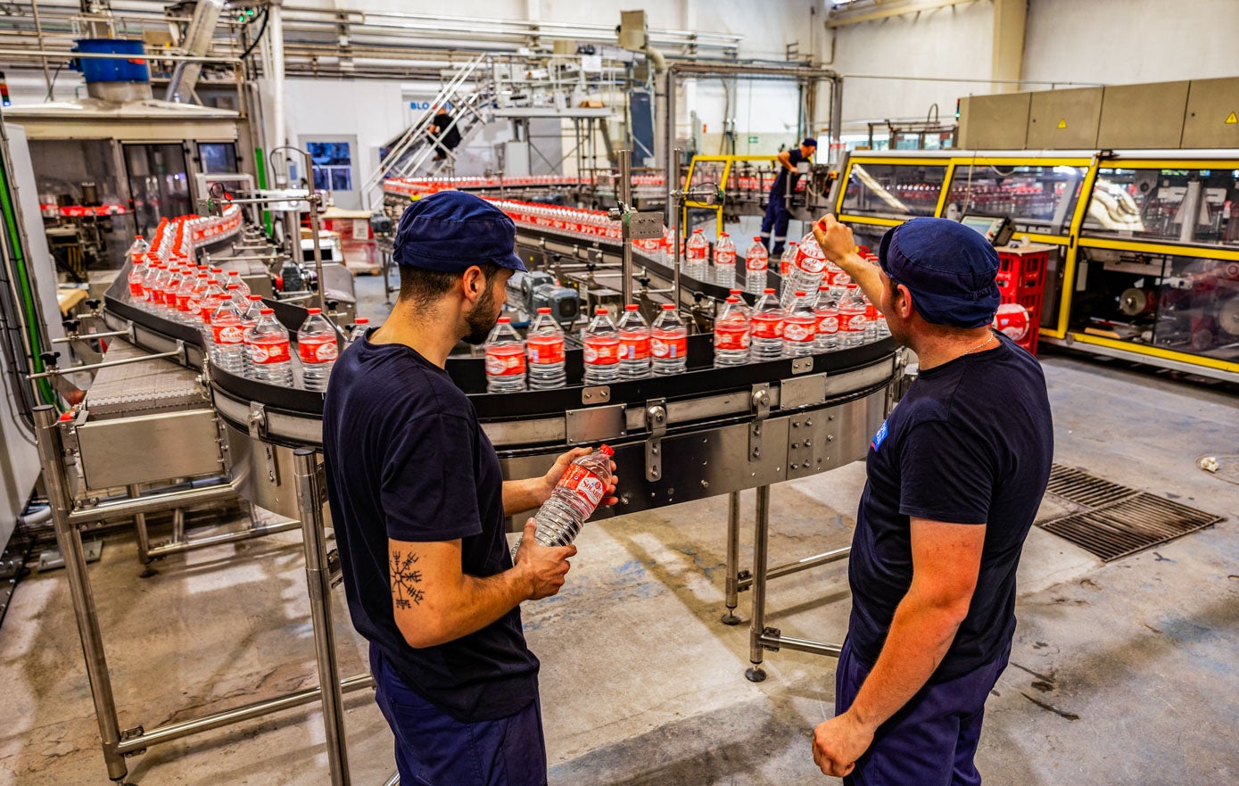 Trabajadores de la embotelladora comprueban que el proceso se desarrolle correctamente.