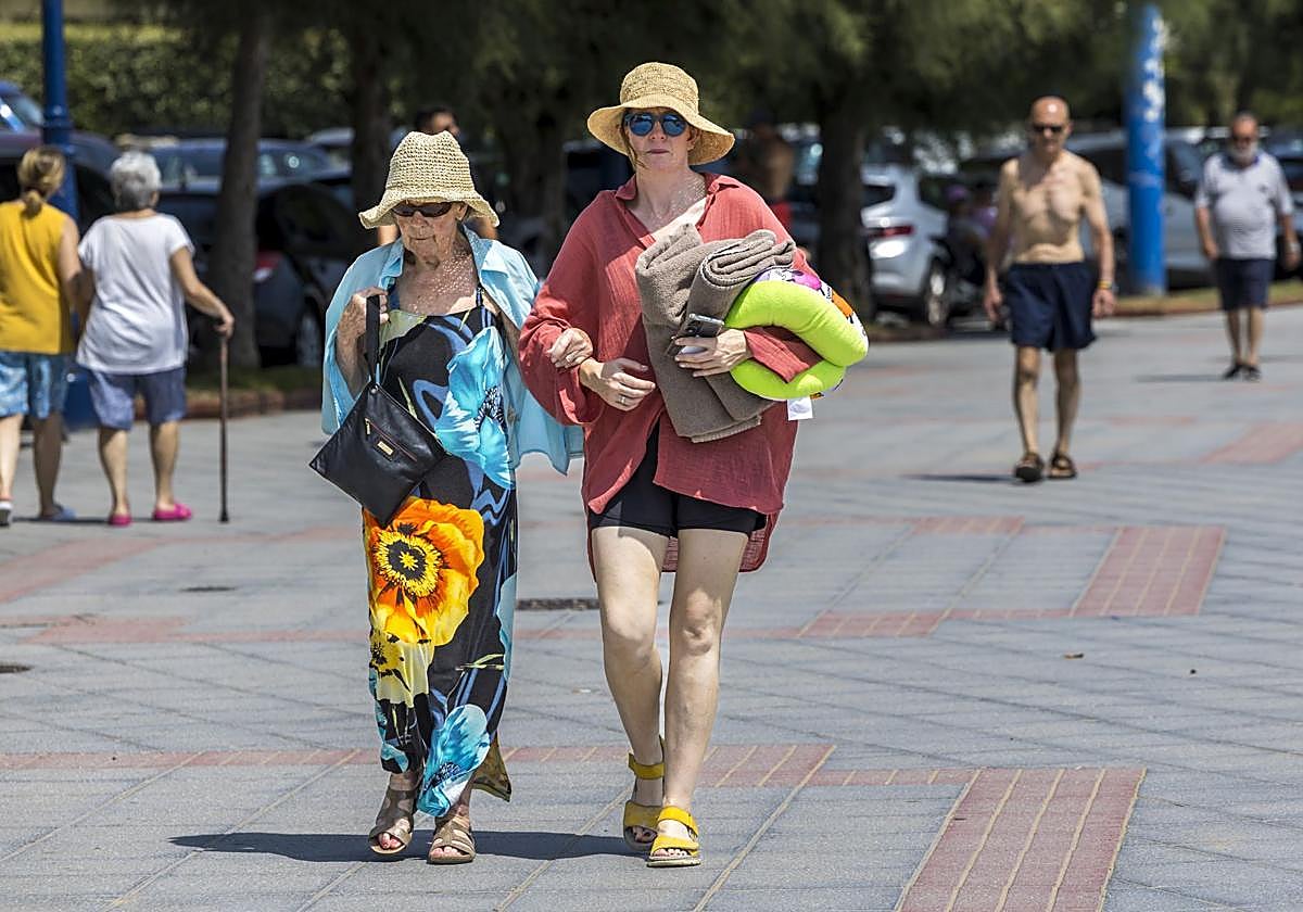 Dos mujeres pasean por la Segunda Playa de El Sardinero con toalla en mano.