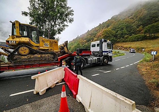 Un camión tráiler transporta un buldócer escoltado por la Guardia Civil para hacer un cortafuegos en el puerto de San Glorio.