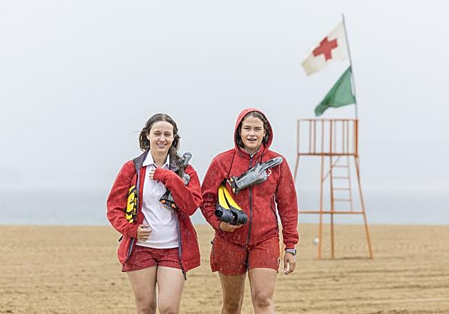 Dos socorristas caminan bajo la lluvia sin bañistas en la playa.