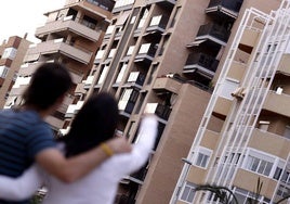 Una pareja que busca alquilar una vivienda señala un bloque de pisos.