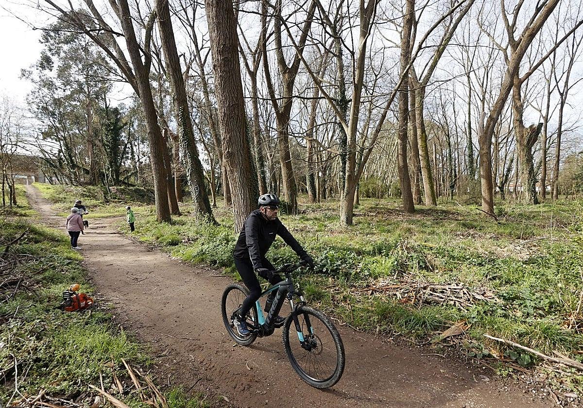 Un vecino circula con su bicicleta por una de las sendas del parque de Las Tablas, en Torrelavega.
