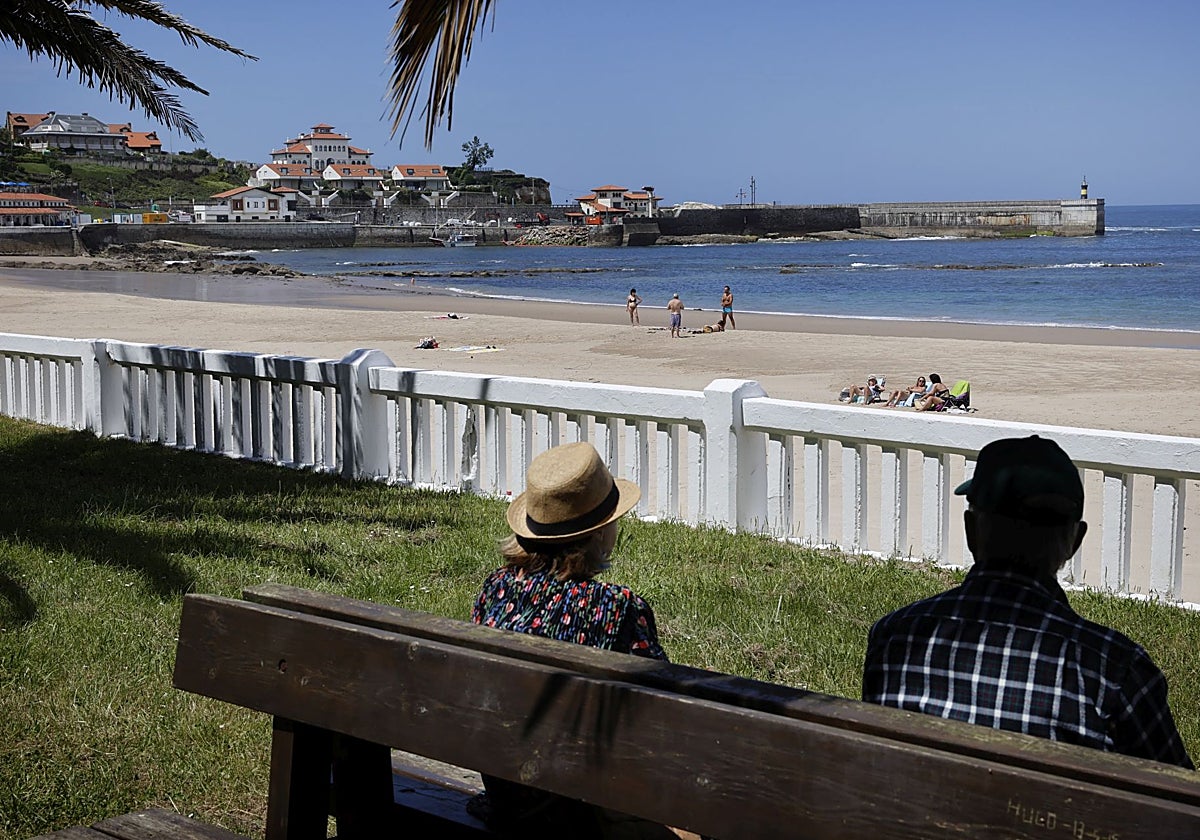 Dos personas en uno de los bancos de la zona de los pinares, junto a la playa de Comillas.
