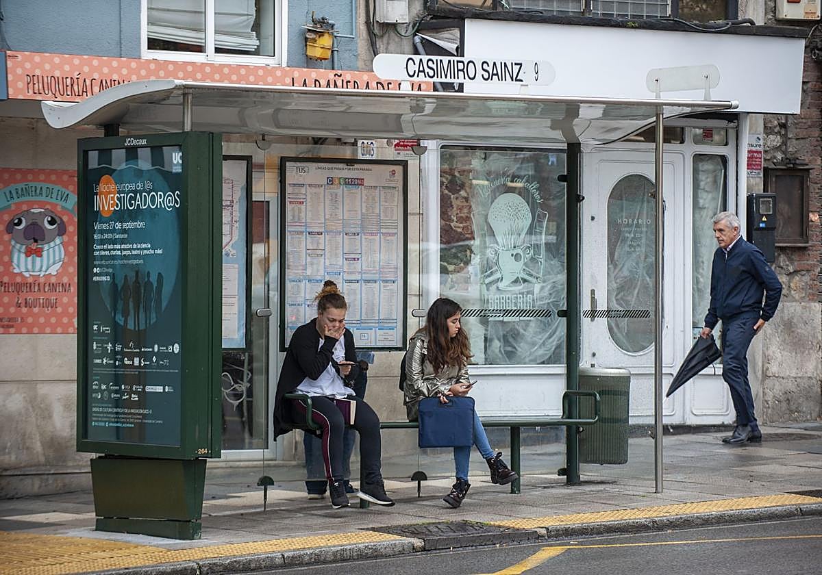 Dos usuarias del TUS esperan su autobús en una marquesina de Casimiro Sainz.