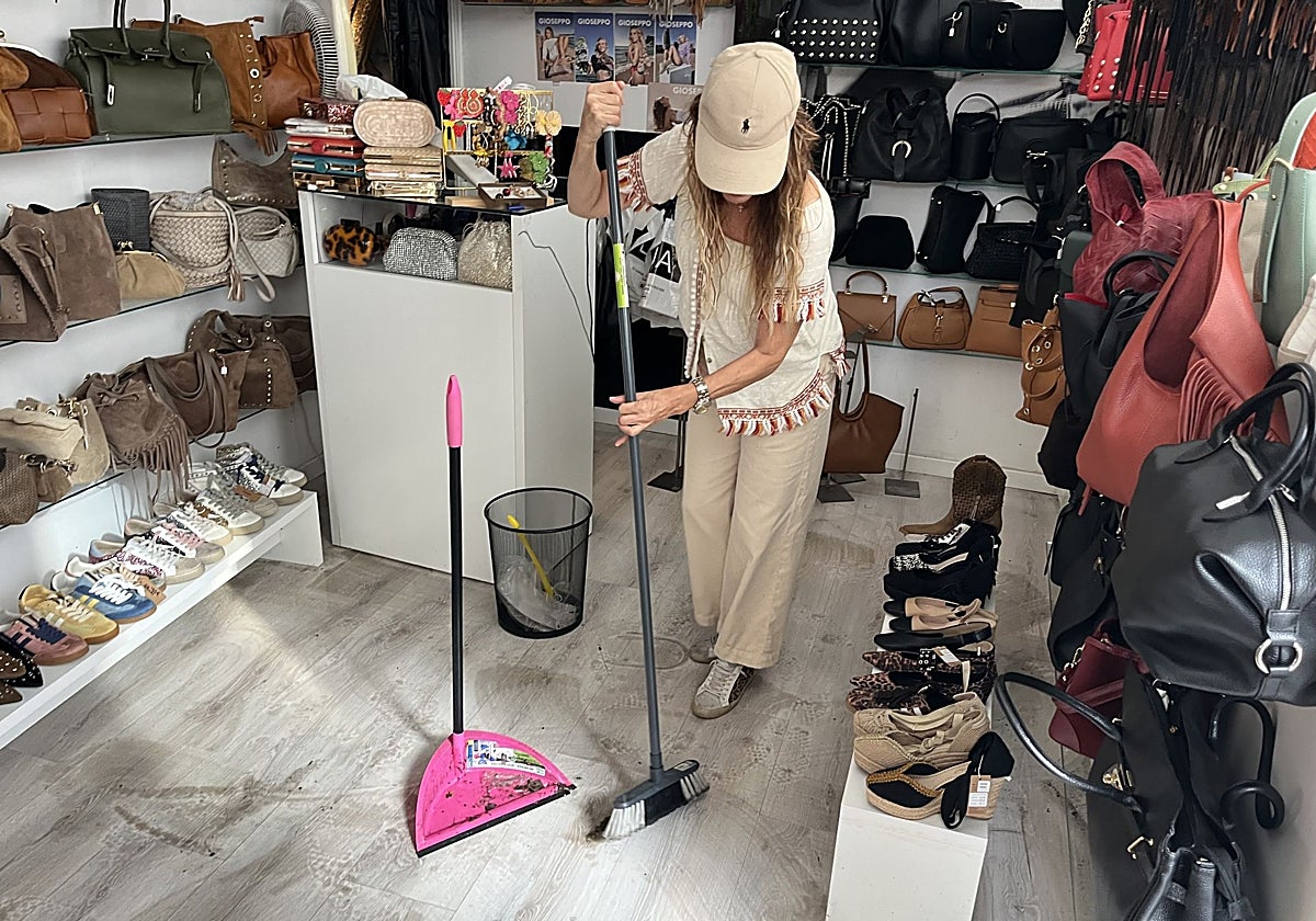 Carmen retira el agua y el barro acumulado en su tienda de zapatos y complementos.