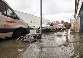 Un hombre achica agua como puede en el polígono de Candina en Santander