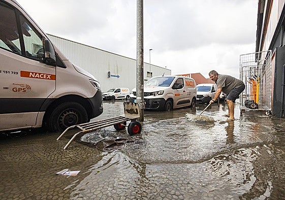 Un hombre achica agua como puede en el polígono de Candina en Santander