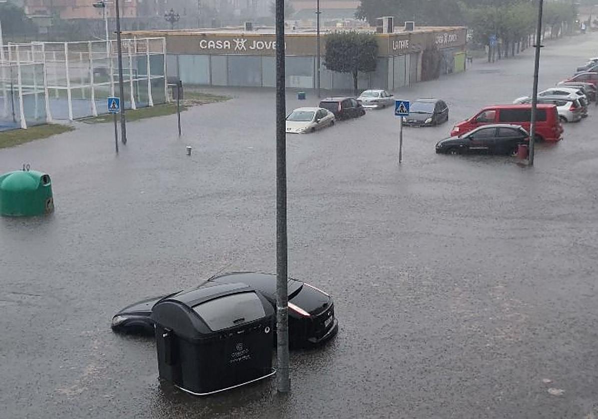 Enorme balsa de agua que cubre los coches en medio del aguacero, en la zona del Parque de Cros, en Maliaño.