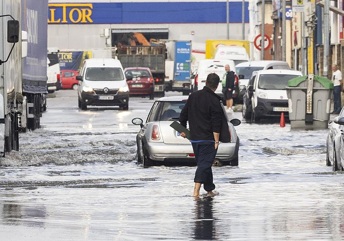 Un hombre camina con el agua a la altura de los tobillos en el polígono de Candina de Santander.