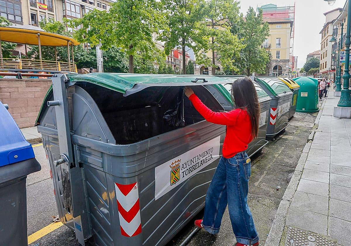 Una mujer deposita basura en un contenedor de la calle Francisco Díaz.