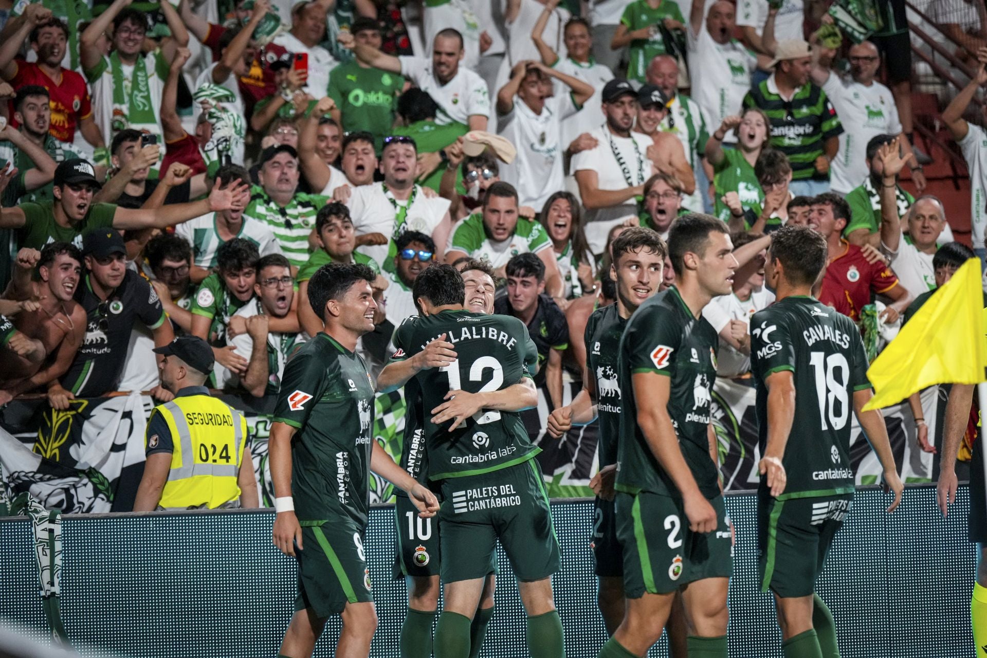 Los jugadores del Racing celebran con la afición desplazada el tercer tanto verdiblanco. 