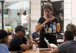 Una camarera atiende a los clientes de una terraza.