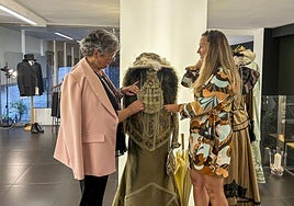 María José Mínguez y su hija, Irene Coté, junto a uno de los trajes de la exposición que se puede contemplar en el Pasaje de Saro de Torrelavega.