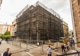 Vecinos caminan junto al edificio, ya en fase de demolición, entre las calles Ave María y Serafín Escalante de Torrelavega.