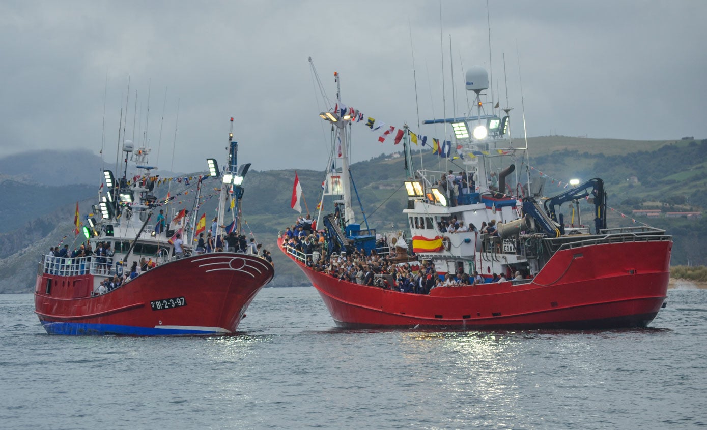 Un barco desfila delante del buque que porta a la Virgen del Puerto para las bendiciones