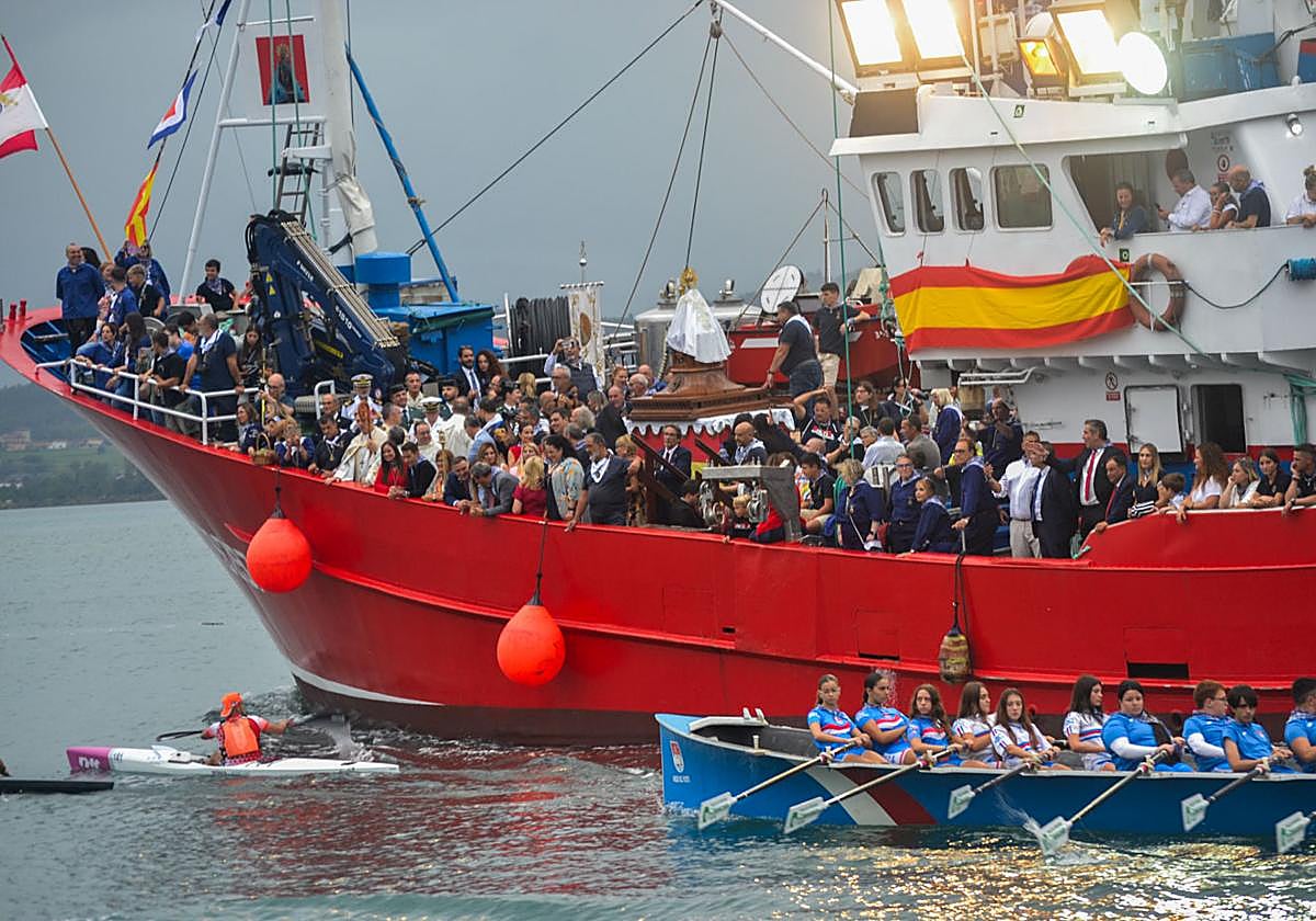 La trainera de remo pasa junto al barco Nuevo Libe, que portó a la Virgen del Puerto por las aguas de la bahía.