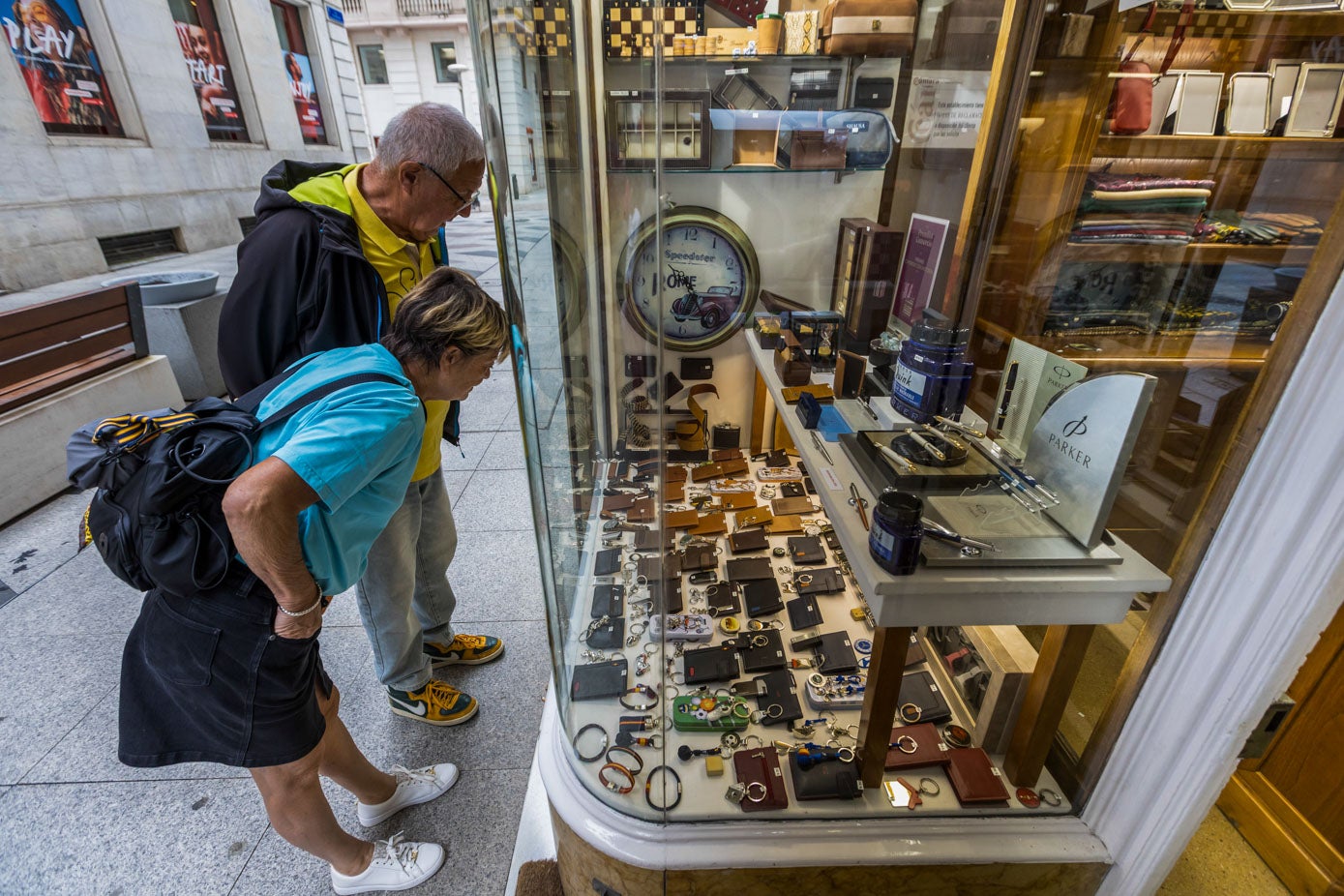Un par de peatones se paran a mirar las carteras que están expuestas en el escaparate de Regalos Pico.