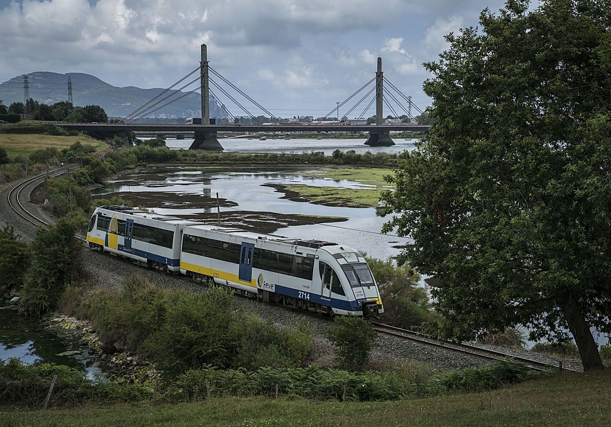 El tren camino de Santander, a punto de pasar bajo el viaducto de Treto, en las marismas de Santoña y Joyel.