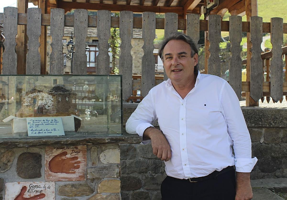 El alcalde de Vega de Pas, Juan Carlos García Diego, junto al monumento al sobao en la plaza del pueblo.