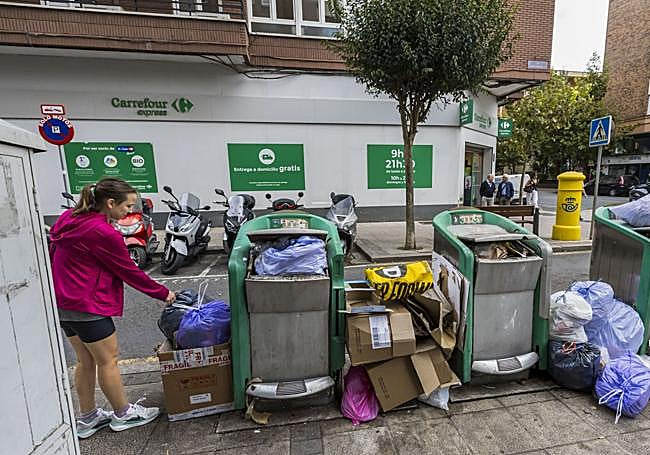 Una chica deposita, ayer a las 11.30 horas, una bolsa de basura en los contenedores neumáticos de la calle Marqués de la Hermida 14, que están hasta arriba de bolsas debido a una avería en la maquina de aspiración.