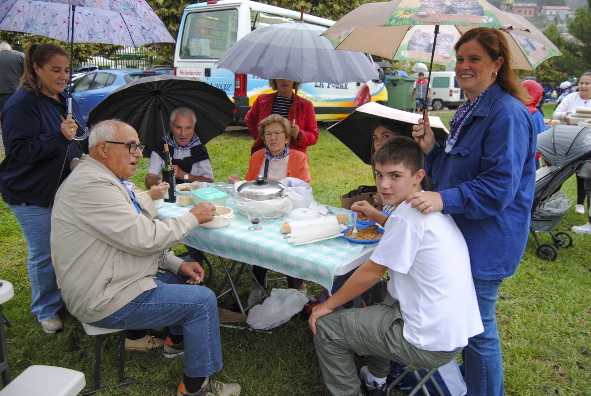 Los más valientes han plantado la mesa y la silla para degustar el guiso bajo los paraguas. 