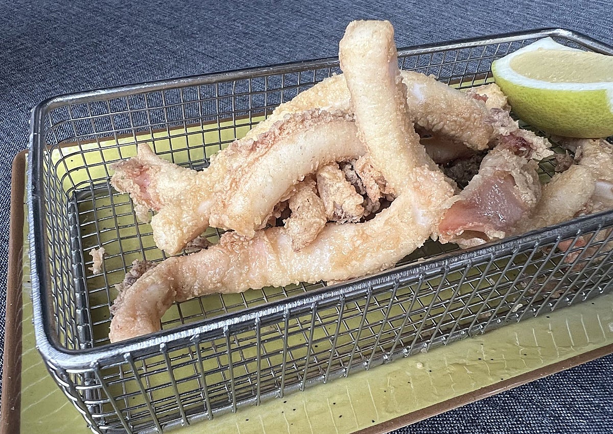 Imagen secundaria 1 - Rafael Cimiano y Aida Fernández, propietarios junto a algunos de los platos que presentan en carta: media ración de rabas y unos tacos de bonito con huevo escalfado, cebolla y foie.