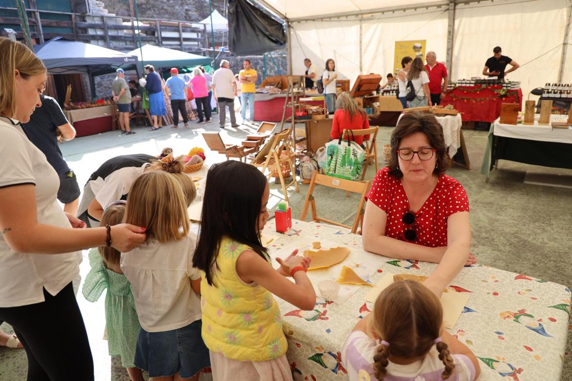 Una mujer enseña a los más pequeños a realizar velas con la cera de las abejas. 