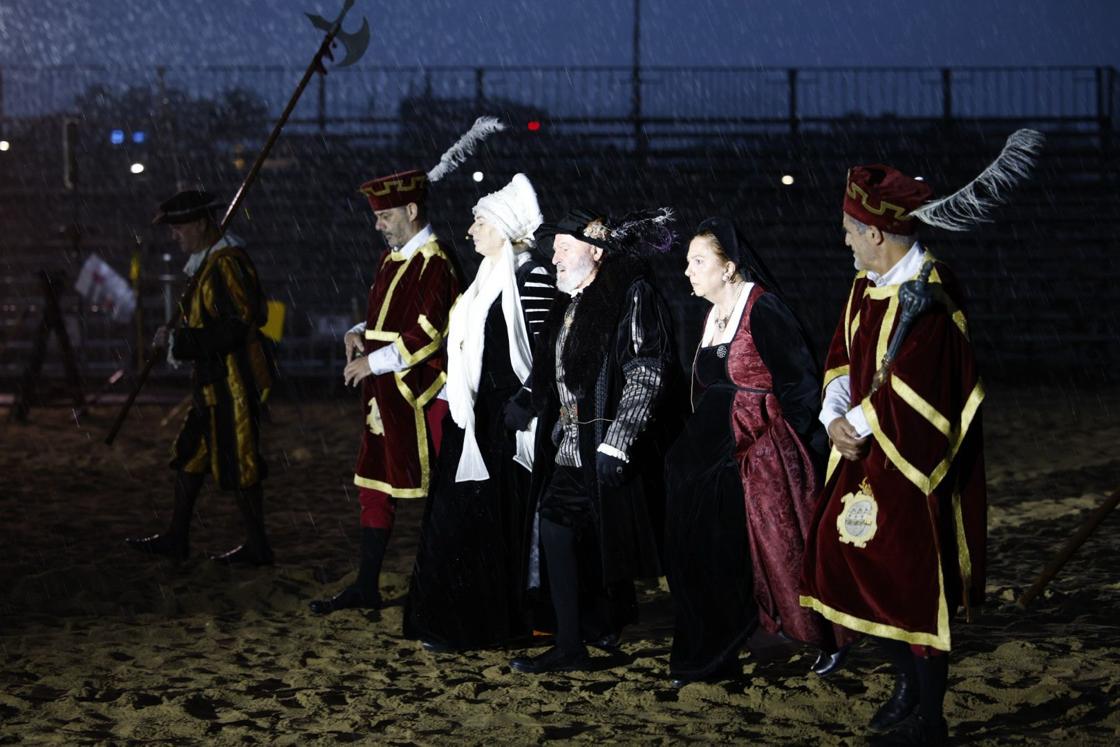 El emperador escolatado por sus hermanas sobre la playa de la Salve, en una representación que se hizo más corta por la lluvia.